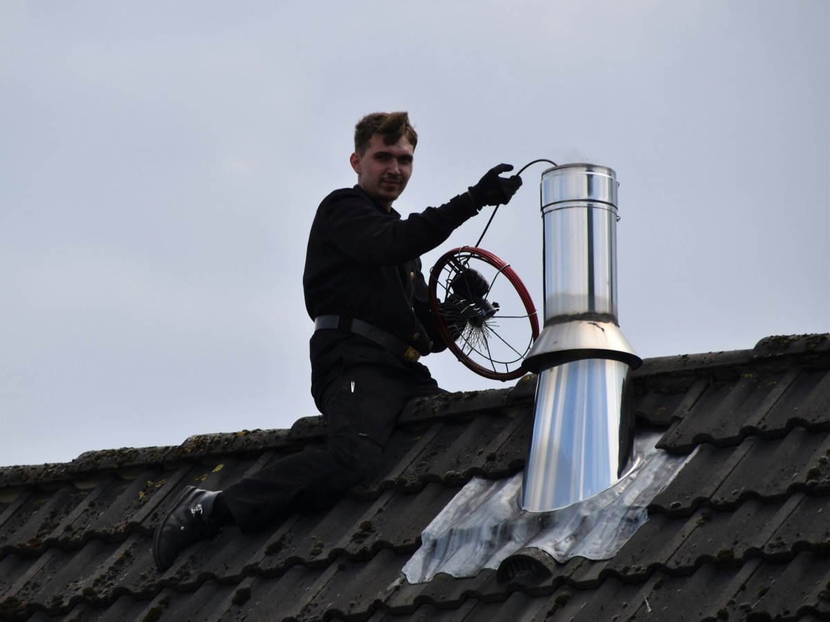 Professional chimney sweep working on a residential rooftop